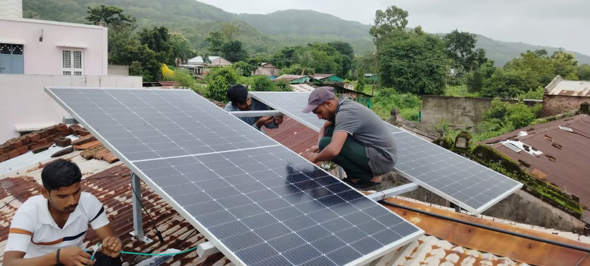 In Churu, Rajasthan, a family walks past a small house featuring a solar panel on its roof, promoting environmental sustainability.